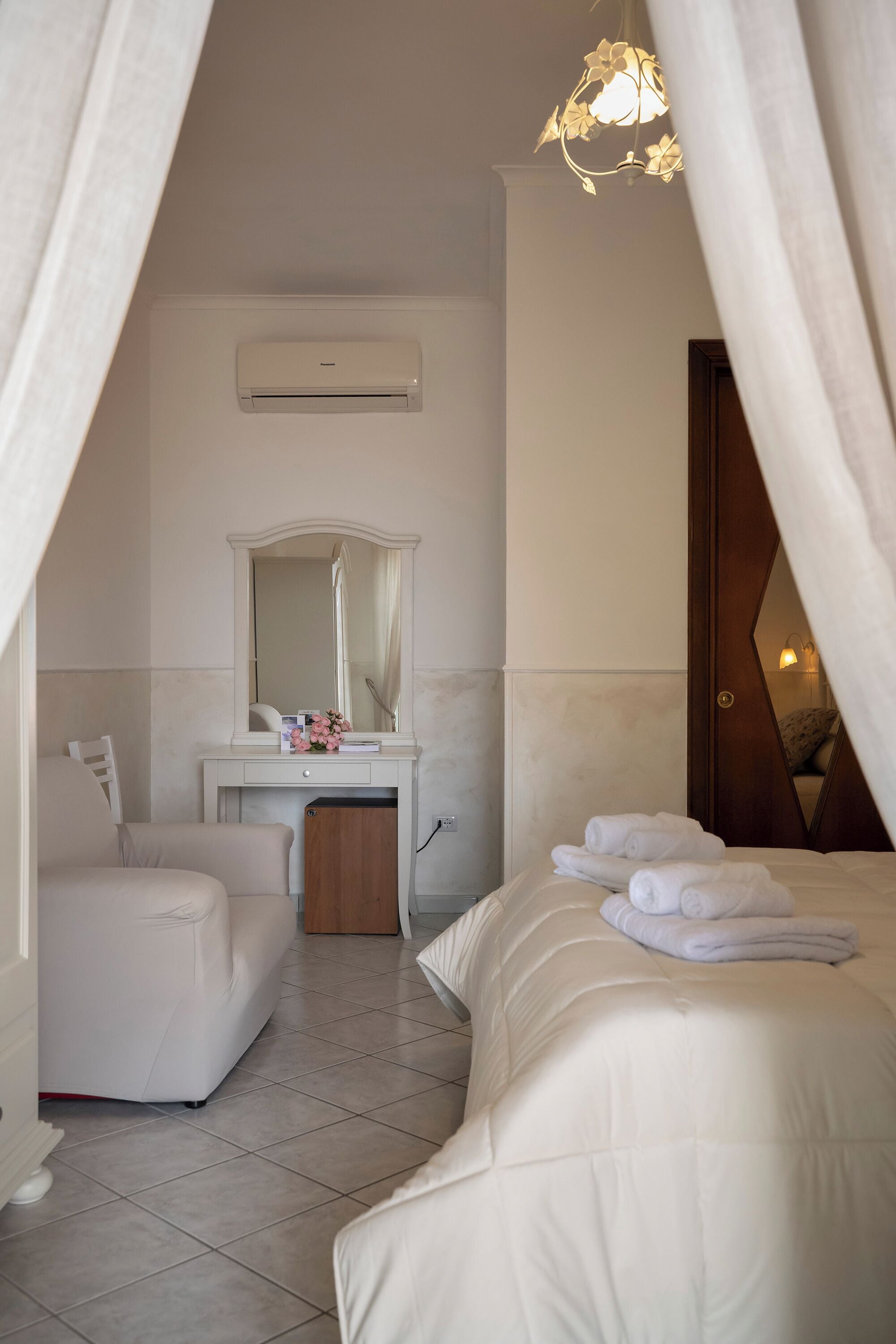 Una habitación de hotel con una cama, un tocador con espejo, una silla y una mesita de noche.