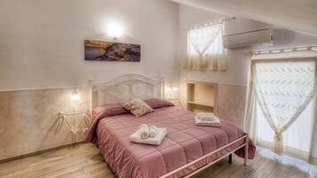 Un dormitorio con cama, lámparas de noche, mesita de noche, aire acondicionado de pared y ventana con cortinas.