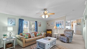 A living room with a sofa, armchair, coffee table, and ceiling fan. - Clari's Place: 6mins to Holden Beach/Pets/Boat Parking/Plenty of Coastal Charm! (Supply)