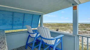 Ein überdachter Außenbereich mit zwei Adirondack-Stühlen, Blick auf den Strand und einem Rauchverbot-Schild.