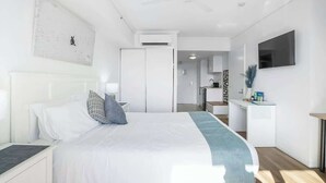A modern hotel room with a bed, bedside table, and a TV mounted on the wall. - Cairns Central Getaway: A Sleek City Studio (Cairns)