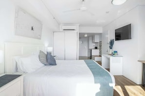 Una camera d'albergo moderna con un letto, un comodino e una TV a parete.