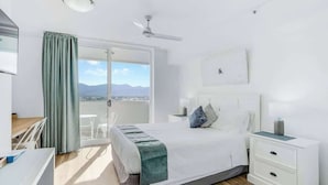 A hotel room with a bed, bedside tables, a desk, and a view of the outdoors. - Cairns Central Getaway: A Sleek City Studio (Cairns)