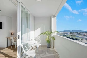 Un balcon avec une table et des chaises, un pot de fleurs et une vue sur la ville.