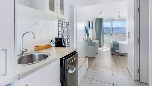 A modern kitchen with a dishwasher, a sink, and a countertop with a coffee maker. - Cairns Central Getaway: A Sleek City Studio (Cairns)