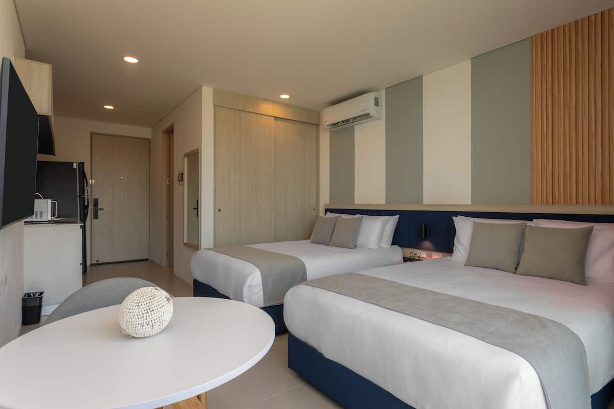 Une chambre d’hôtel avec deux lits, une petite table, un four à micro-ondes et un téléviseur.