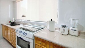 A kitchen with a stove, toaster, and blender on the counter, and a window providing natural light. - Bright & Spacious 3-BR-2BTH, near WTC/ Insurgentes (Ciudad de México)