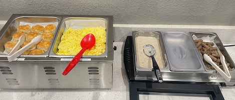 Ein Buffet mit gekennzeichneten Speisen, darunter Kekse, Rührei und Fleisch.