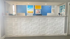 A reception desk with a white panel design, blue walls, and framed artwork. - Homegate Inn And Suites Collierville TN (Collierville)