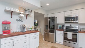 A modern kitchen with white cabinets, stainless steel appliances, and a wooden countertop.