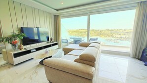 Ein modernes Wohnzimmer mit Sofa, Fernseher und Blick auf einen Hafen.