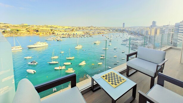 Ein Balkon mit Blick auf eine Marina voller Boote, mit Blick auf eine Stadtlandschaft.