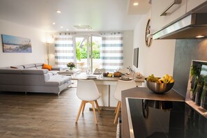 A modern kitchen with a dining area, a sofa, and a view of greenery outside. - Baltic Village - VIP-Haus (Damp)