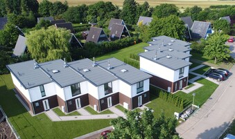 A modern residential building with multiple units, each featuring a flat roof and large windows.
