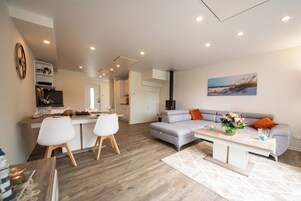 A modern living room with a grey sofa, white chairs, a coffee table, and a painting on the wall.