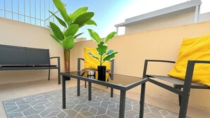 Ein Balkon mit einer Couch, einem Tisch, Stühlen und einem Blumentopf.