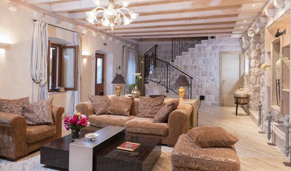 A spacious living room with a sofa set, a coffee table, and a staircase leading to an upper level.