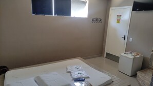 A hotel room with a bed, a small bedside table, a window, and a door. - Motel Classe A  (Limeira)