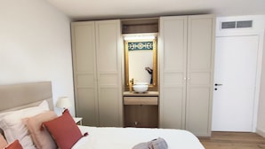 A hotel room with a bed, a wardrobe, a bathroom with a sink and mirror, and a towel on the bed.
