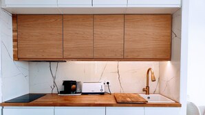 A modern kitchen with wooden cabinets, a marble backsplash, a toaster, and a sink with a gold faucet.
