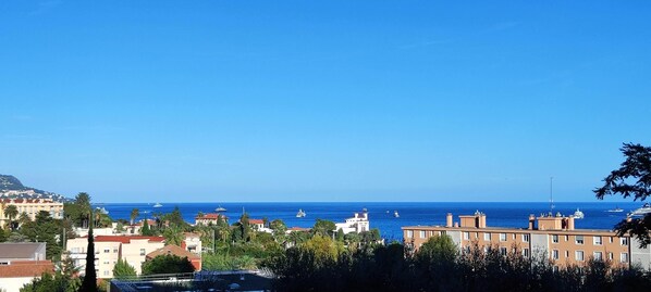 A coastal cityscape with buildings, a clear blue sky, and the sea.