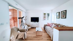A modern living room with a sofa, a coffee table, a TV, and a telescope.