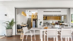 A modern open-plan living space with a dining area, kitchen, and staircase.
