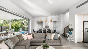 A modern living room with a sectional sofa, dining area, and kitchen.