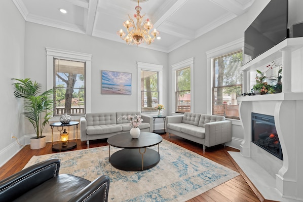 A spacious living room with a fireplace, two sofas, a coffee table, and a chandelier.