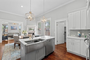 A modern kitchen with a central island, white cabinetry, and pendant lighting.