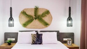 A neatly made bed with white and dark pillows, a woven wall hanging, and two hanging light fixtures. - Villa Eleonas with private swimming pool (Rethymno)