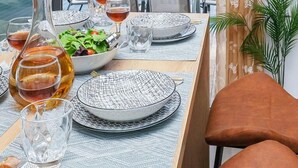 A dining area with a table set for four, a bottle of wine, glasses, and a bowl of salad. - Villa Eleonas with private swimming pool (Rethymno)