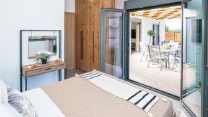 A modern bedroom with a bed, bedside table, and a large window. - Villa Eleonas with private swimming pool (Rethymno)
