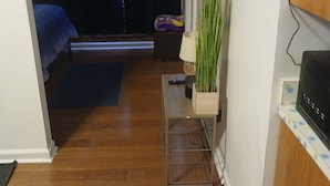 A room with a bed, a small table with a plant, a TV, and a curtain.