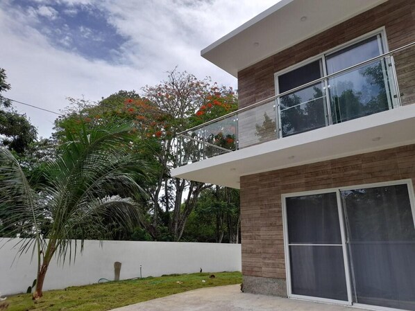 A modern two-story house with a balcony, large windows, and a white exterior wall. - Villa Sleeps 8 With Private Pool (Sosúa)
