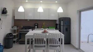 A modern kitchen with white cabinets, a central island with chairs, pendant lighting, a refrigerator, and a coffee maker. - Tropical Villa Escape in Sosua (Sosúa)