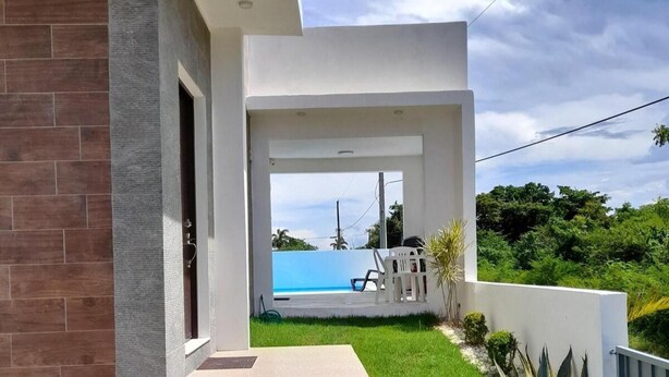 A modern house with a covered patio, a swimming pool, and lush greenery. - Tropical Villa Escape in Sosua (Sosúa)