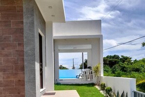 Uma casa moderna com varanda coberta, piscina e vegetação exuberante.