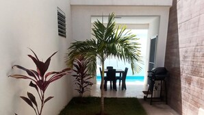 A small, well-maintained outdoor area with artificial grass, a few potted plants, a table and chairs, and a grill. - Sosua Villa Retreat - Calle Pedro Clisante (Sosúa)