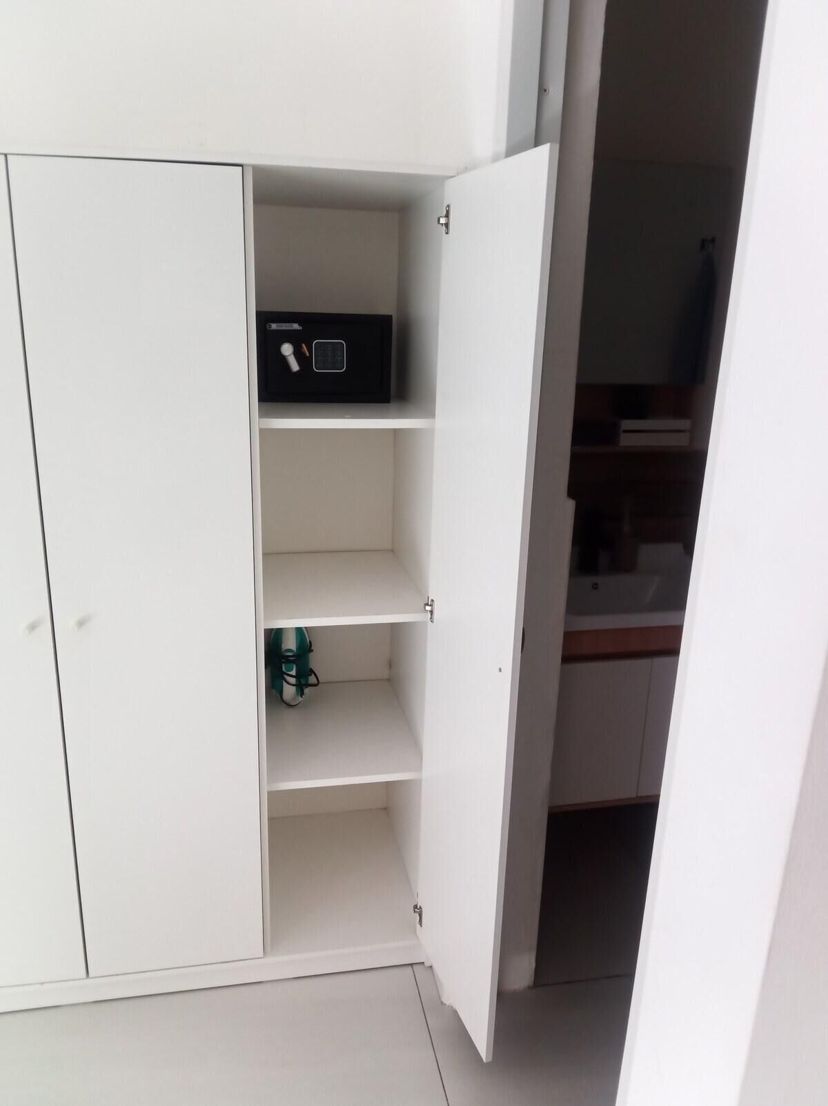 A white wardrobe with open doors revealing shelves and a hanging space.