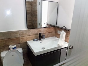 A bathroom with a white sink, a mirror, and a toilet.