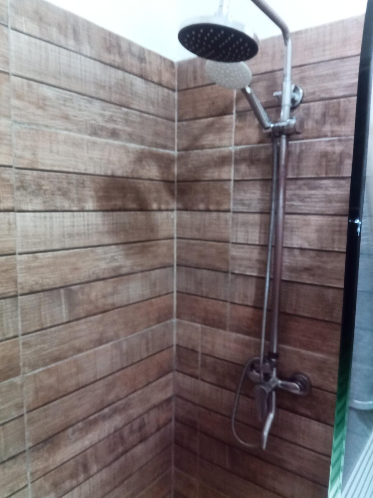 A shower area with wooden panel walls and a handheld showerhead.