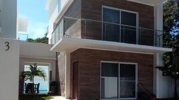 A modern two-story building with a balcony, large windows, and a garage. - Sosua Villa Retreat - Calle Pedro Clisante (Sosúa)