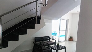 A modern interior with a staircase, a sofa, a coffee table, and a view of a pool through a glass door. - Sosua Villa Retreat - Calle Pedro Clisante (Sosúa)