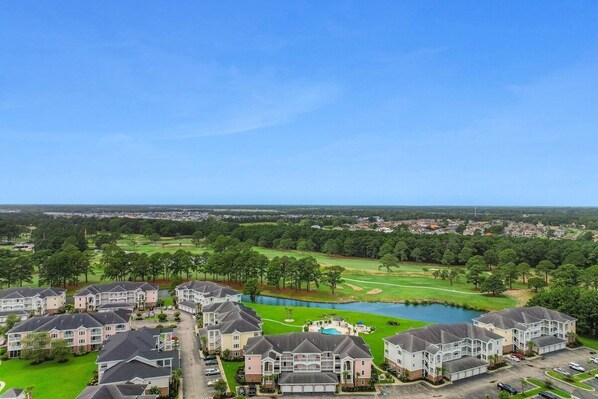 A residential area with multiple two-story houses, a golf course, and a lake.