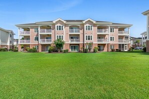 A multi-story residential building with a central courtyard, balconies, and a well-maintained lawn.