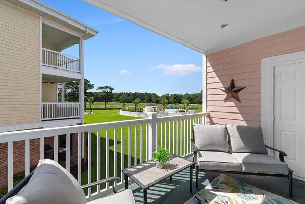 A balcony with a white railing, a grey sofa, a small table with a plant, and a star decoration on the wall.
