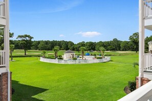 A well-maintained lawn with a gazebo, a small building, and a white picket fence.