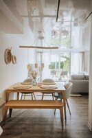 A modern dining area with a wooden table, benches, and a view of the outdoors.
