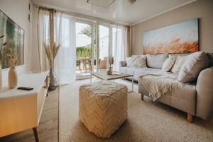 A modern living room with a sofa, ottoman, and a dining area with a table and chairs.